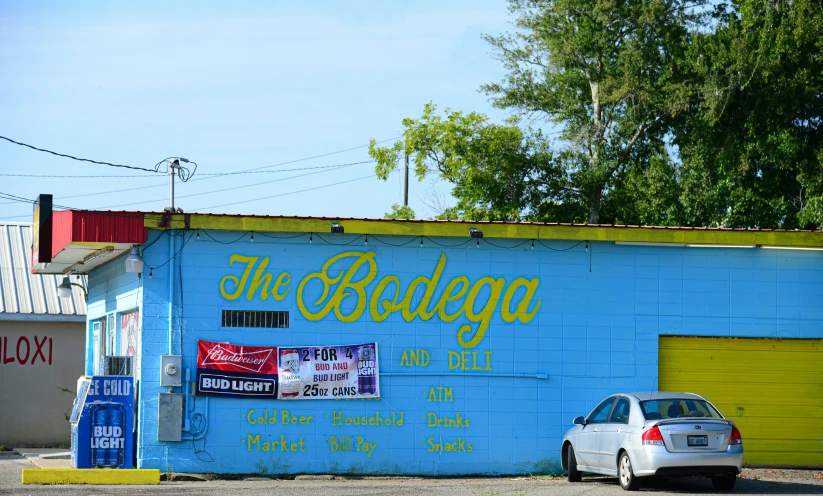 a blue building with graffiti on the side of it and two cars parked in front