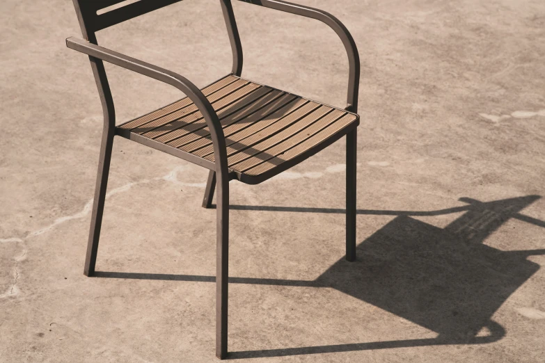 a wooden and metal chair on concrete with the shadow off of the chair