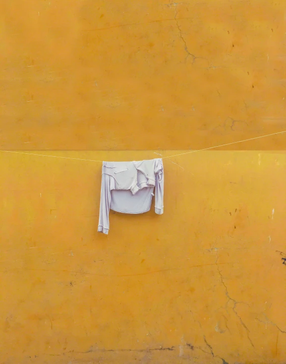 a cloth hangs on a yellow wall as if for clothes