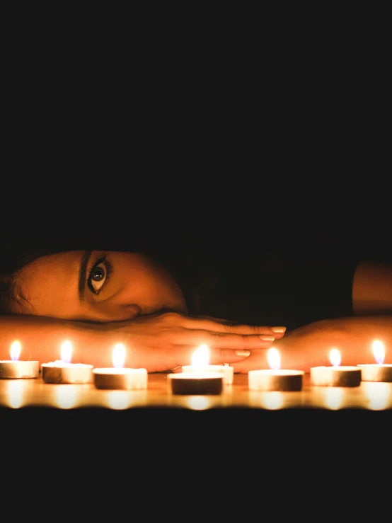 the image of a girl is being reflected in the candle lit candles