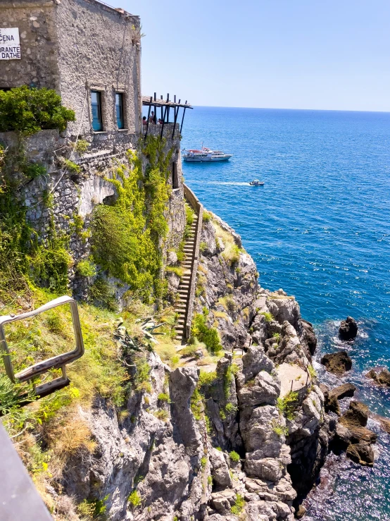 some buildings by the ocean and a boat sailing