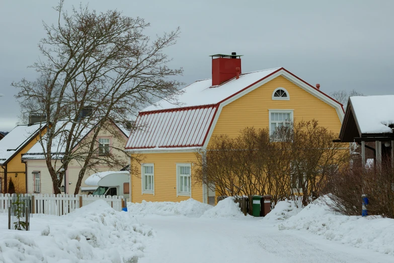 a house is covered with snow outside by a few trees