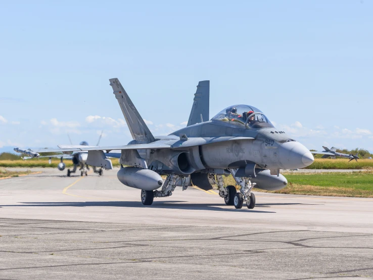 an army style fighter jet parked in front of other airplanes