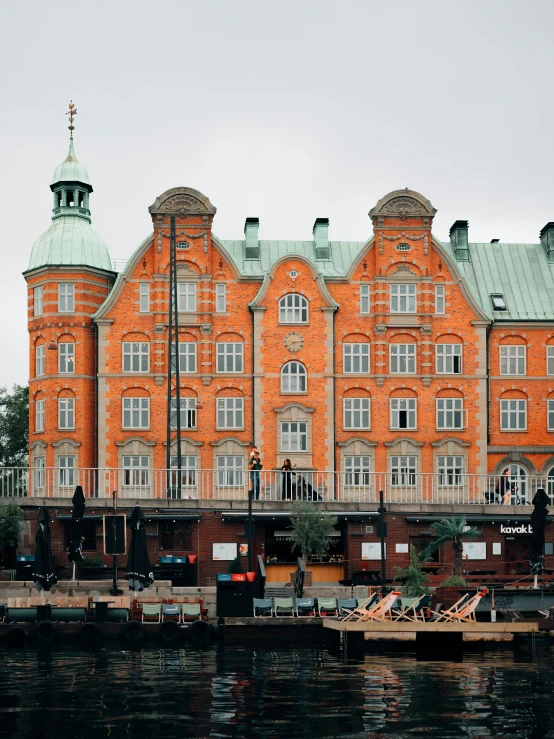 an orange brick building sitting next to the ocean