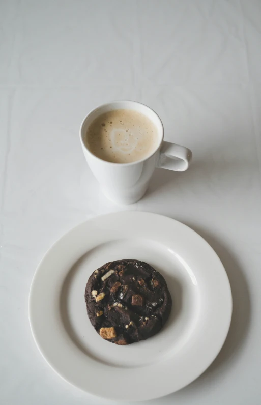 a cookie and cup of coffee on a white table