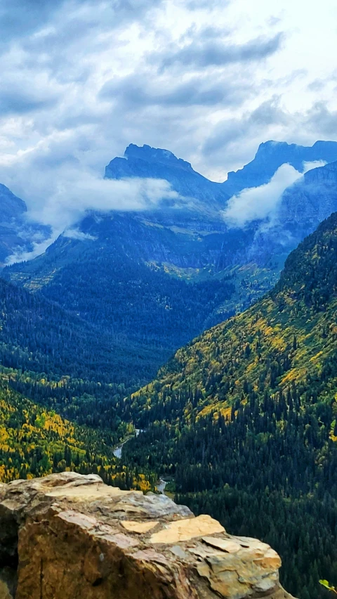 a large rock on top of a mountain with mountains in the background