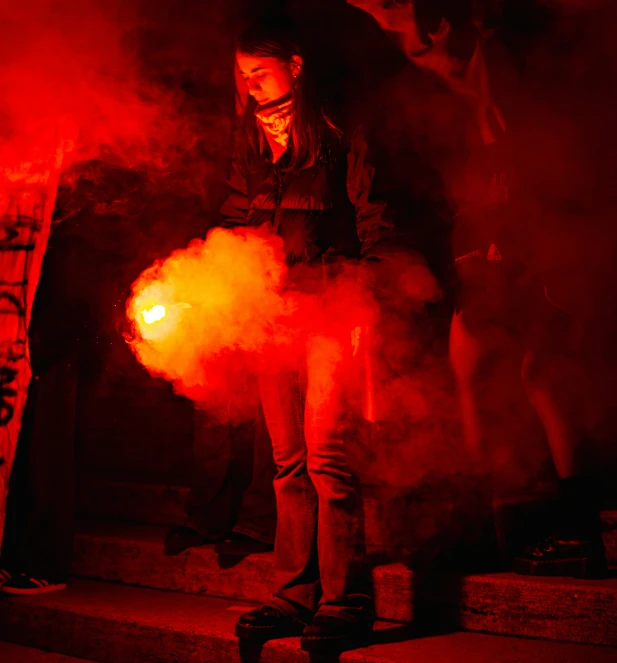 a woman standing next to some red smoke