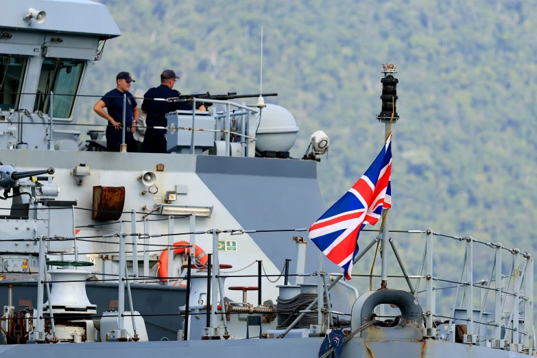 two men are standing on the bow of a battleship