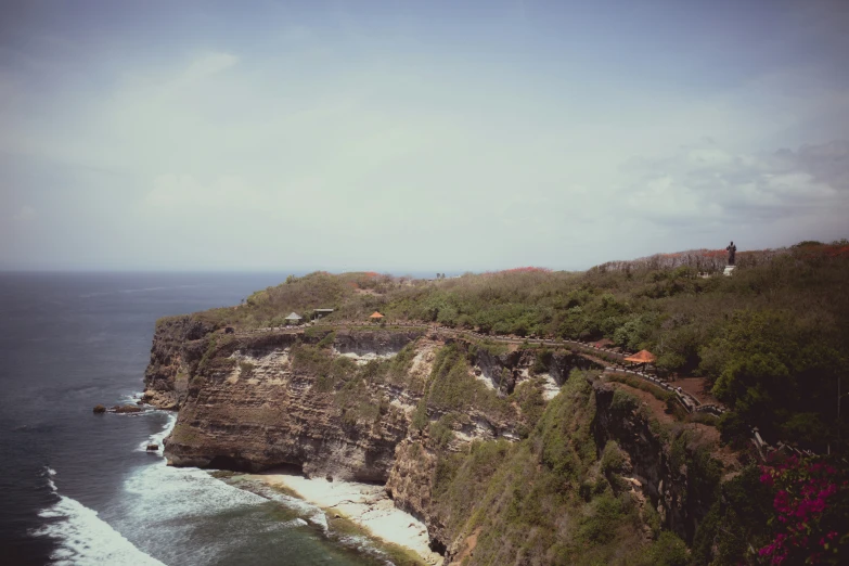 a large cliff over looking the ocean with waves hitting the rocks