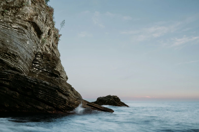 a rock cliff extends to the ocean on a clear day