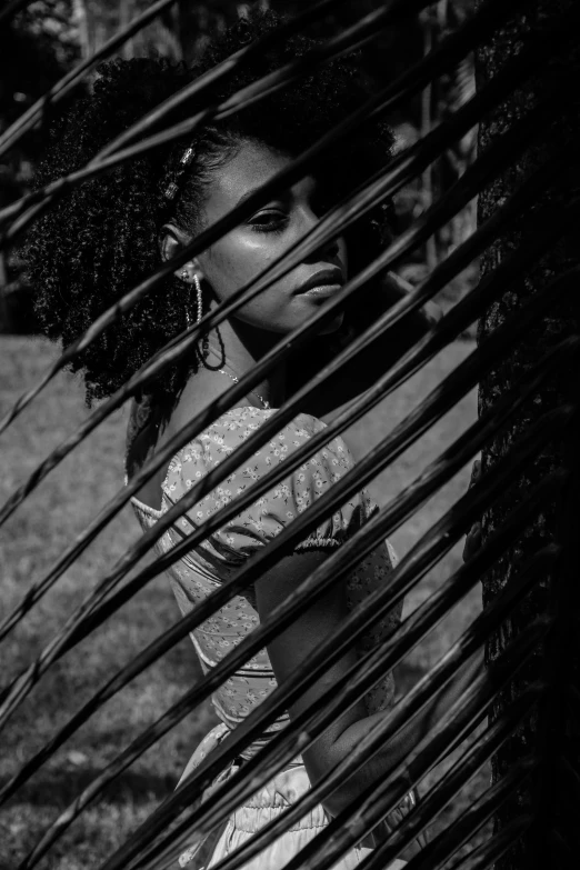 a  with black hair and large earrings stands under the leaves of a palm tree