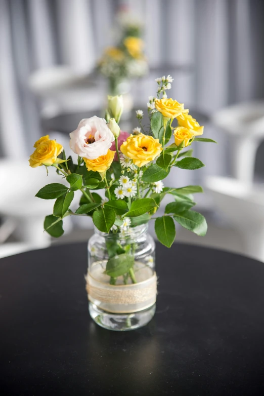 a vase full of yellow and white flowers on a table