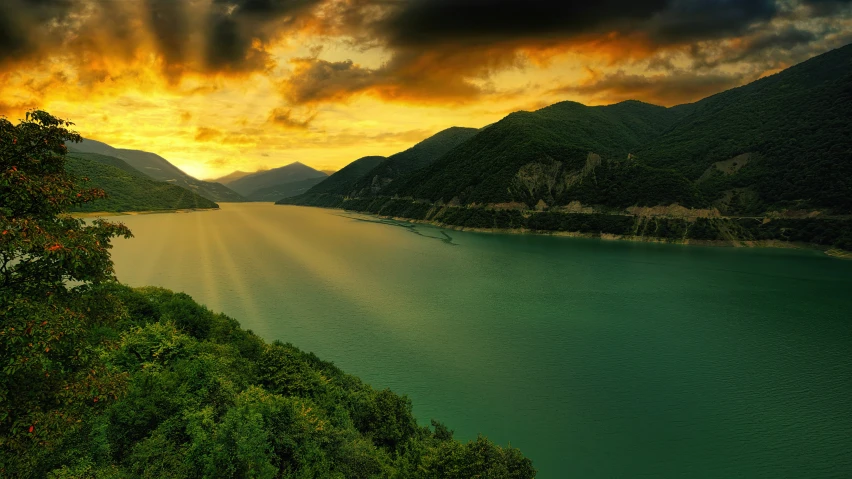 a view of a lake and mountains with the sun shining