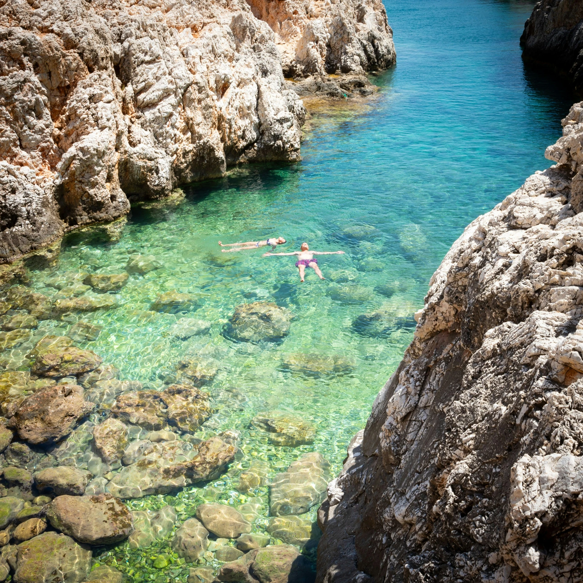 a person standing in some water next to a small rock cliff