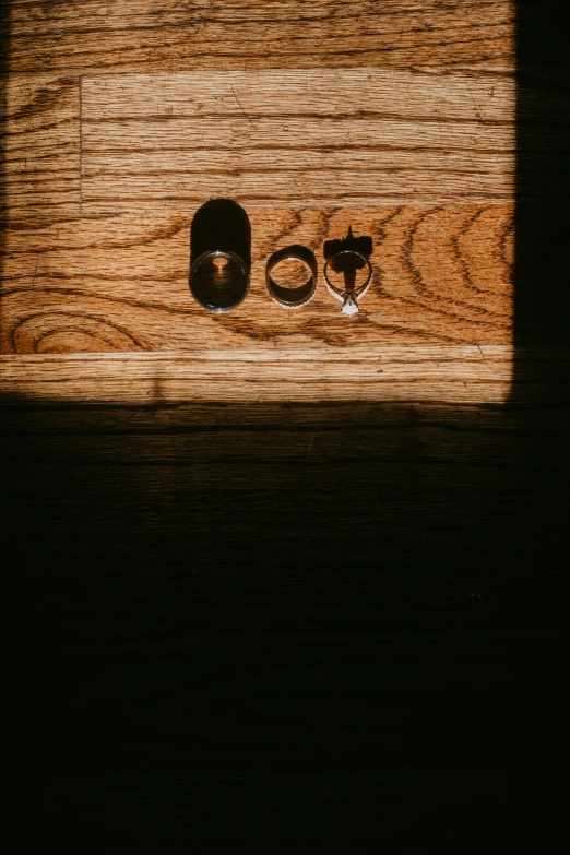 a wooden board is displayed with a couple rings and an object