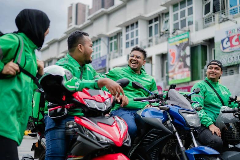 a group of people in green shirts sitting on motorcycles