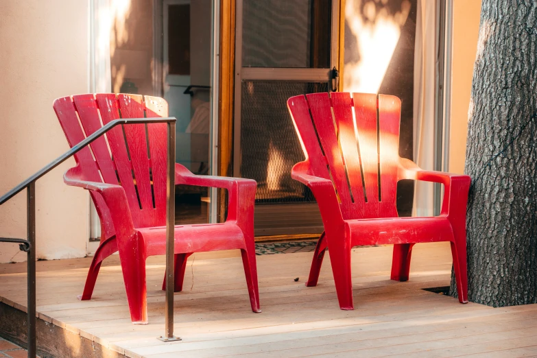 two red chairs near each other on the steps outside a house