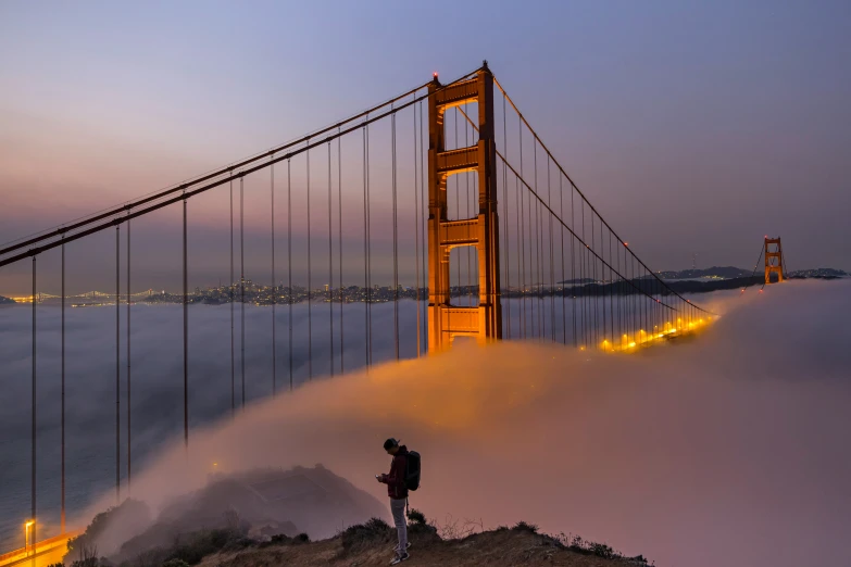 a couple stands on a hill overlooking the golden gate bridge