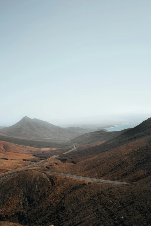 a road in a valley with hills and bushes