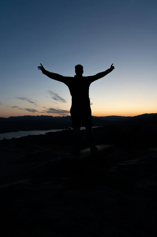 a person stands on top of a cliff with arms wide open