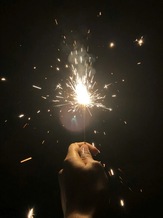 someone holding up sparklers in the dark