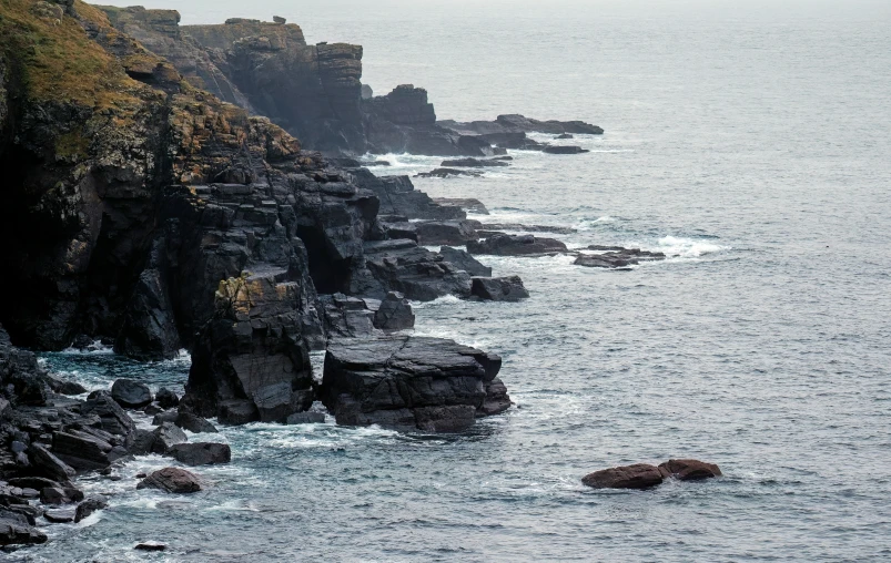 a boat is out in the ocean near a rocky cliff