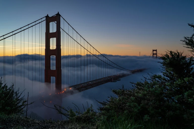 a golden gate bridge surrounded by clouds during sunset