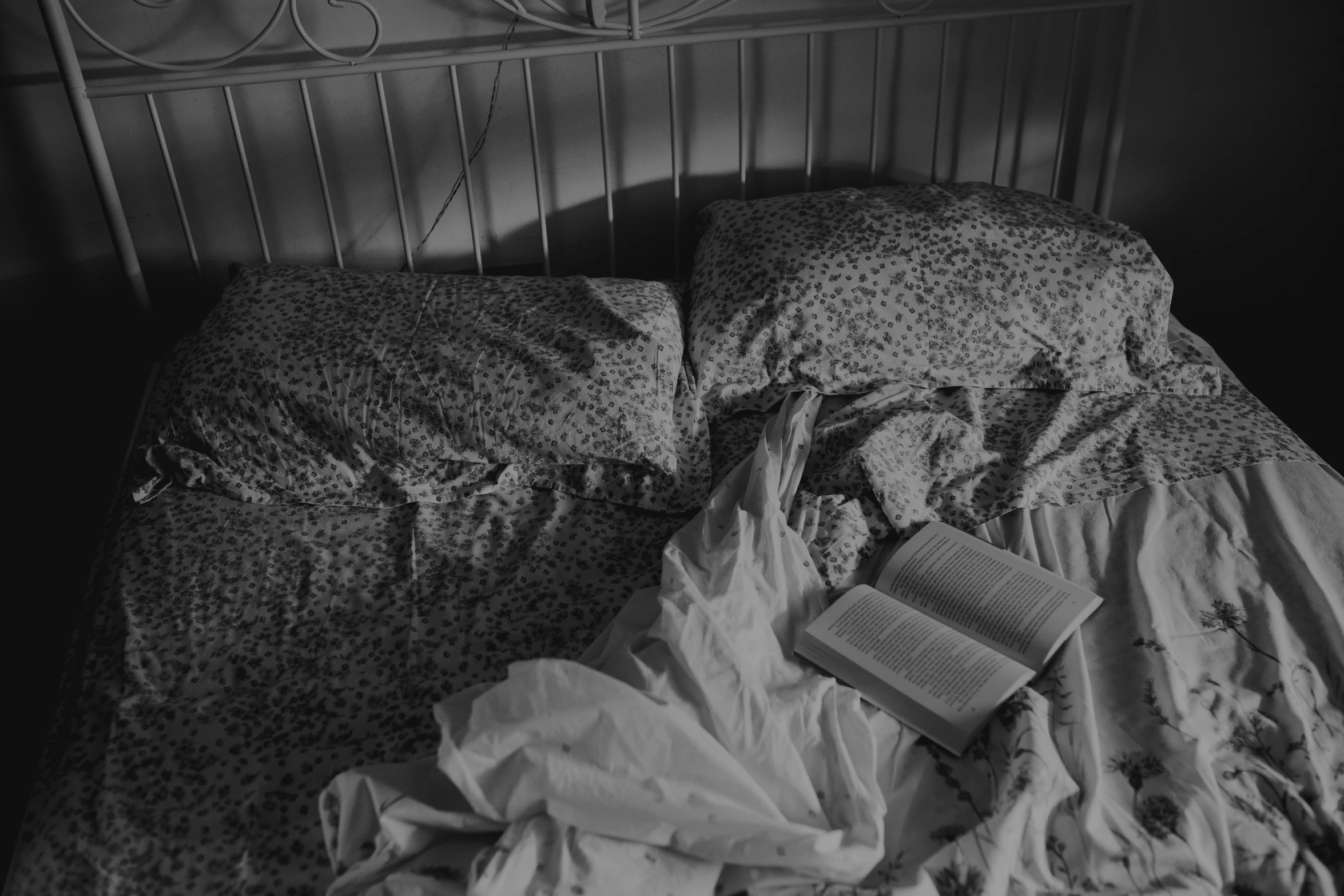 a bed covered in pillows and sheets with a book sitting on top of it