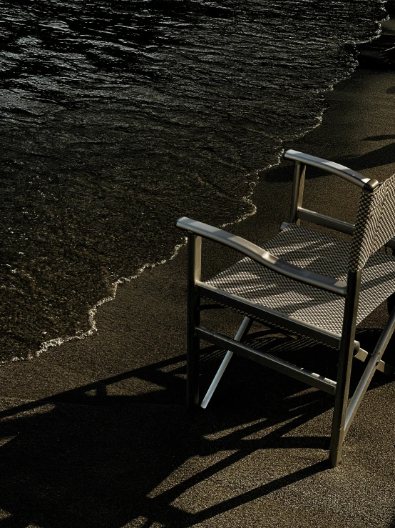 a striped chair next to the beach with sand on it