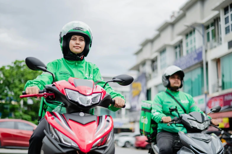 two people in green jackets are riding motorcycles
