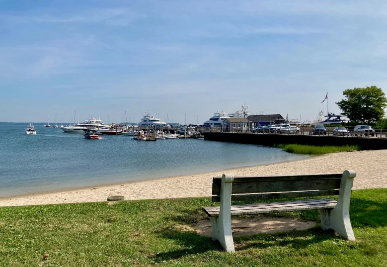 a wooden bench next to the sea with a boat dock in the background