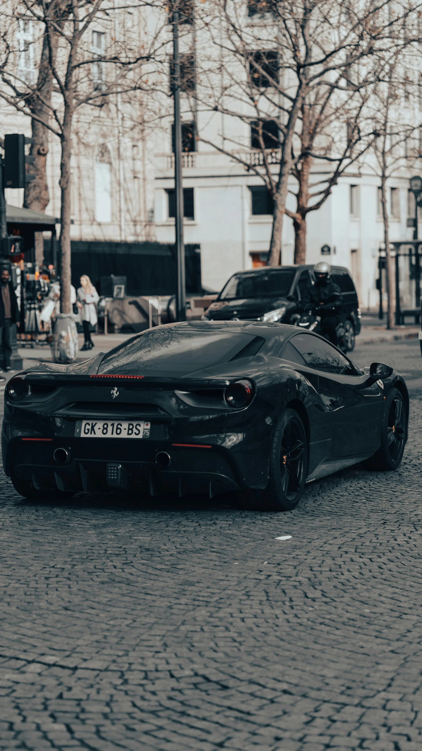 a black car sitting in the middle of a brick road