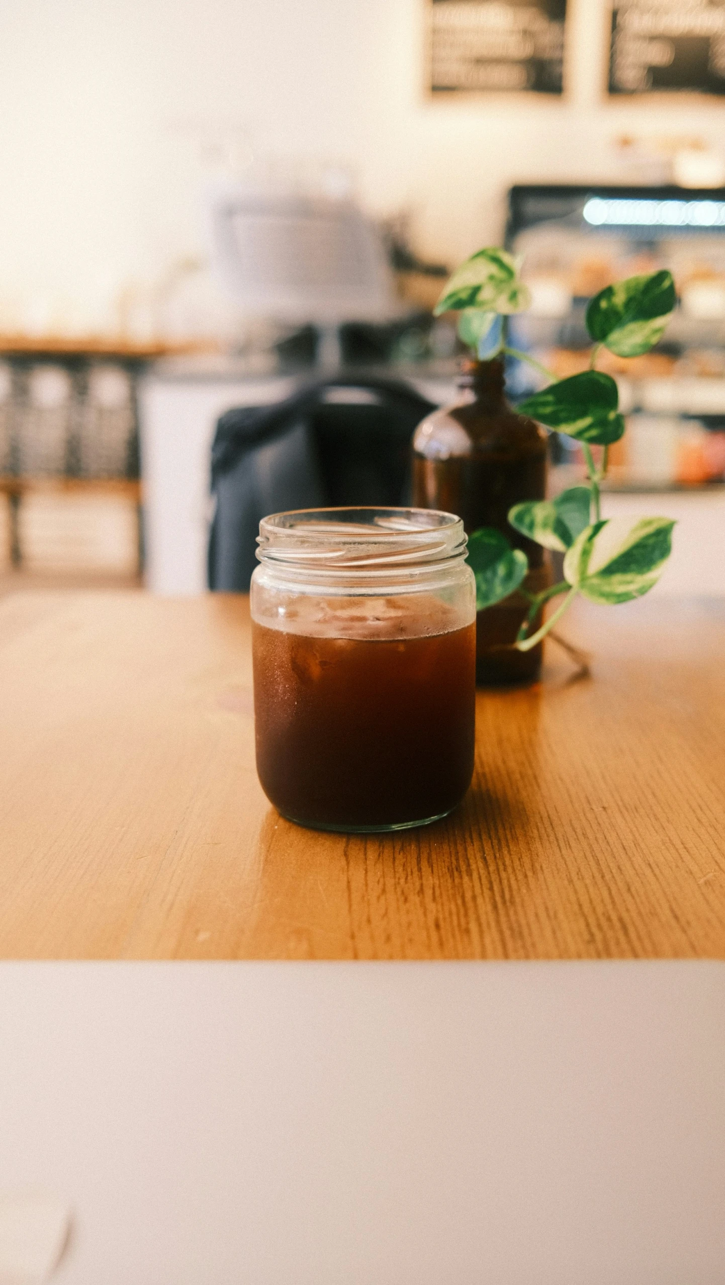 a jar of liquid and a plant on the table