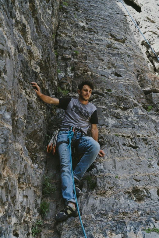 man posing with rope attached to his feet while hanging on a rock