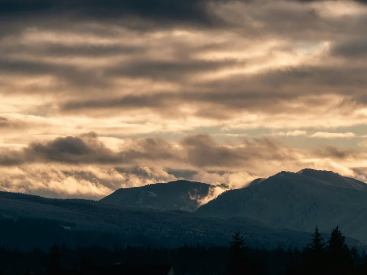 there are many clouds flying over the mountains