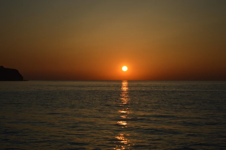 the sun is setting over the ocean from the water