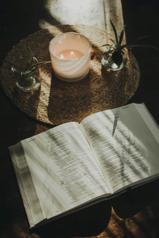 an open book on a table near two lit candles