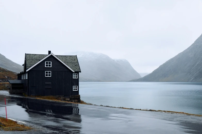 a black cabin with a mountain backdrop in the rain