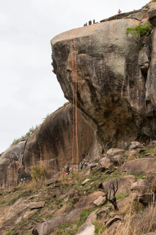 the climber on the side of the large cliff is climbing