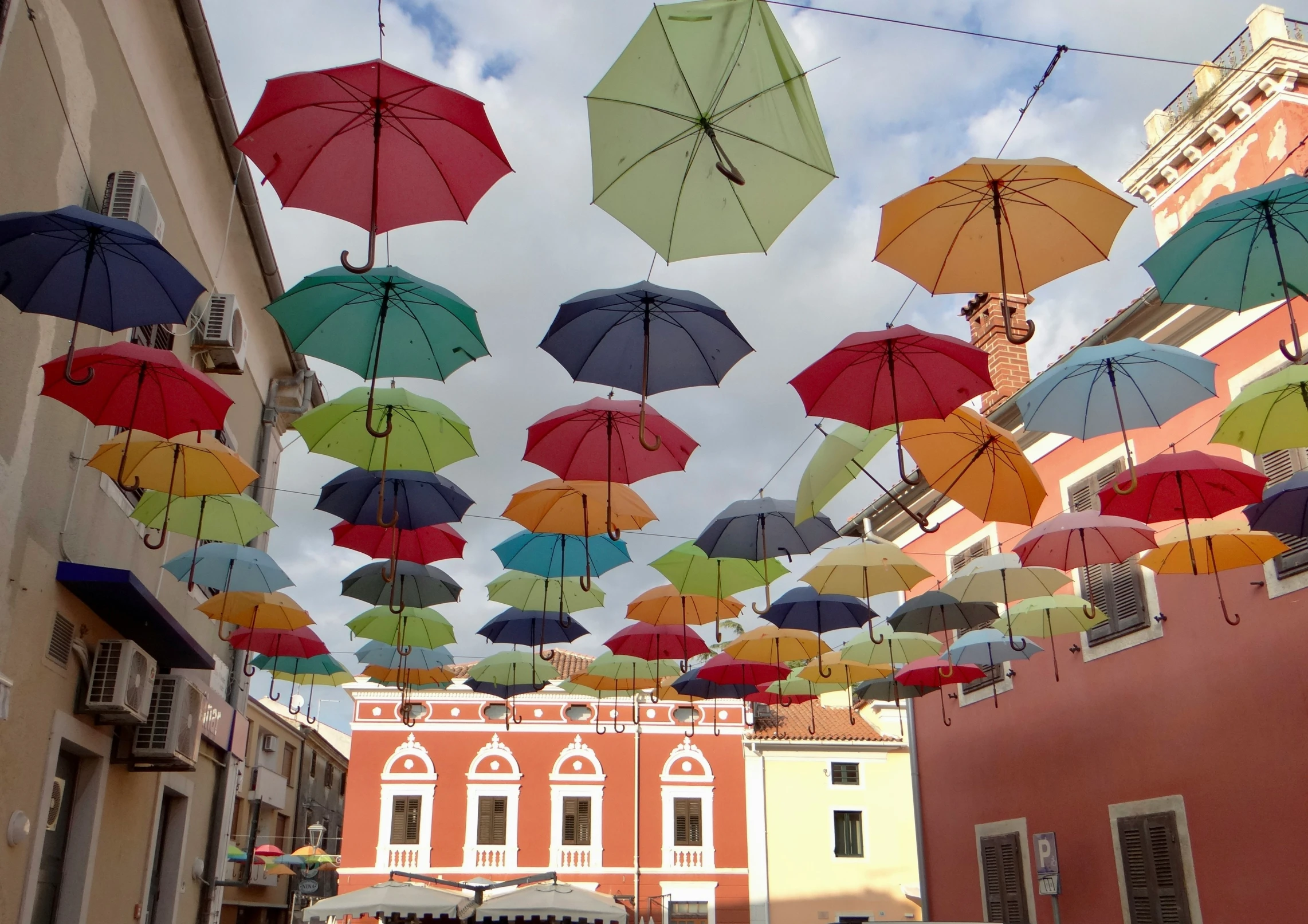 many open and closed umbrellas strung over an alley