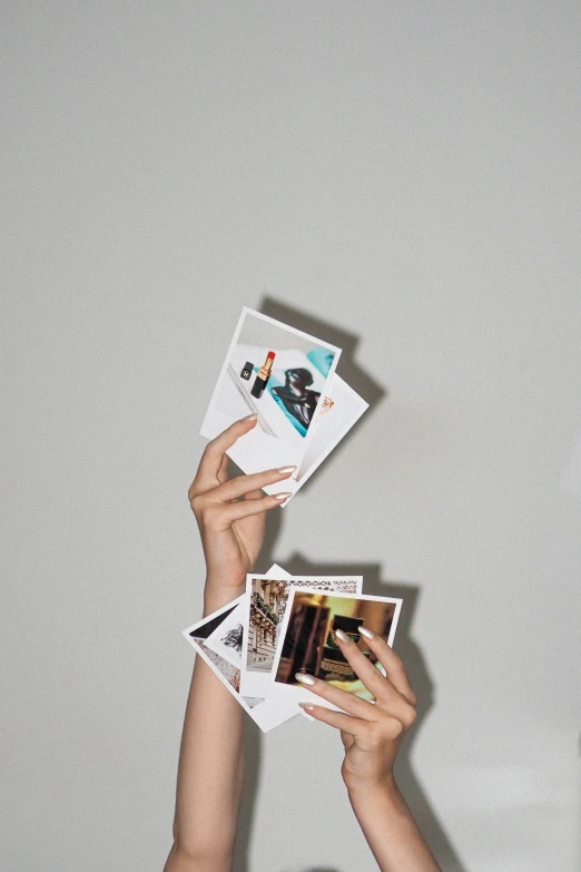 the person is holding up several pictures in their hands