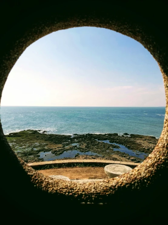 round window in concrete structure overlooking a water landscape