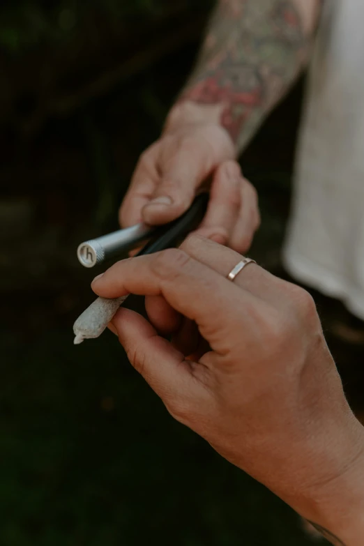a person is holding a cigarette and pointing a pen