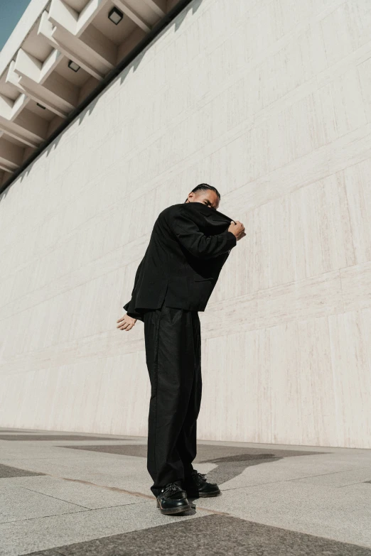 a man in a black suit holding his head with his hands