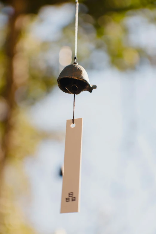 small bell is hanging from a wire with a label