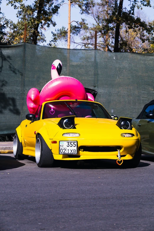 a large inflatable balloon sitting on top of a yellow sports car
