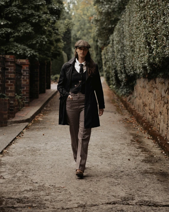 a woman in a black coat and tie walking down the street