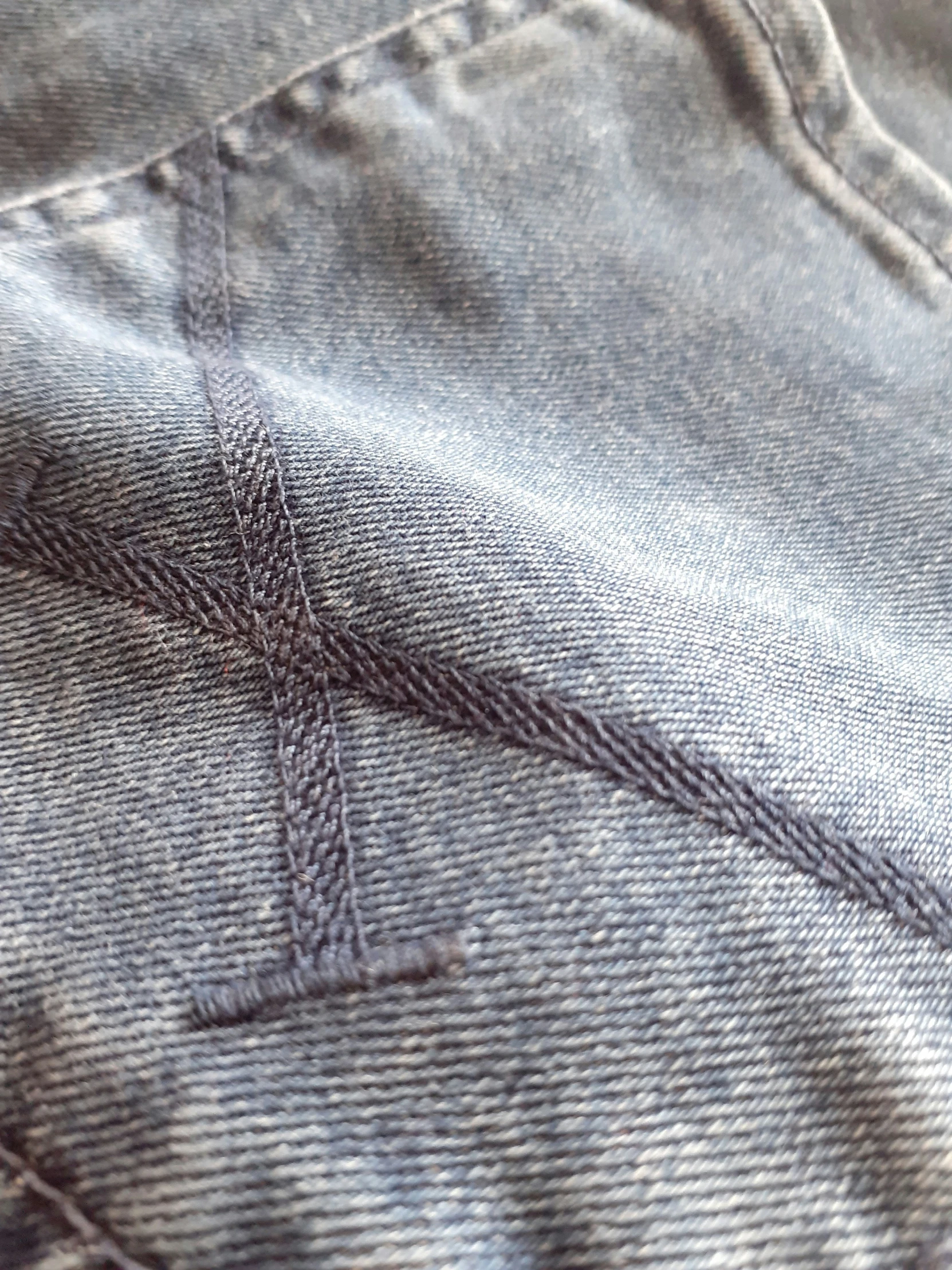 stitchwork on blue jeans with some white pins in it