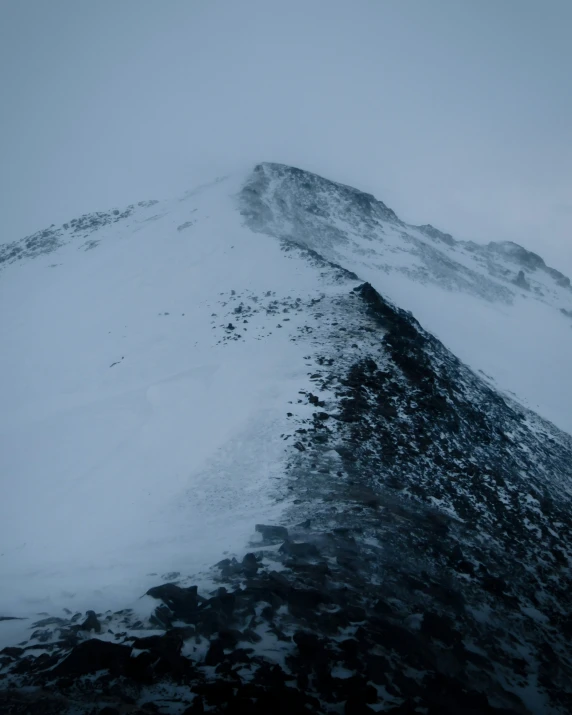 a mountain covered with snow, with some clouds