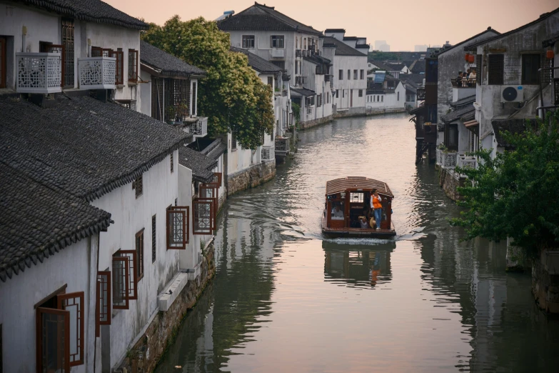 a boat traveling down the river by houses